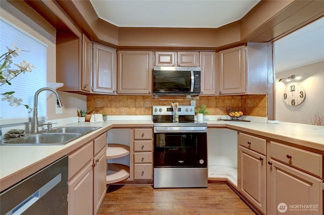 kitchen featuring stainless steel appliances, a sink, and light countertops