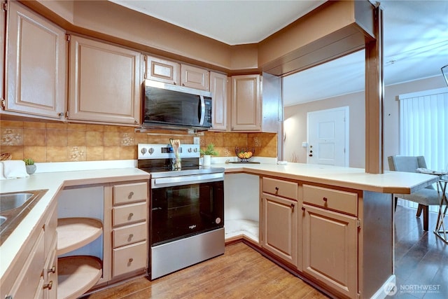 kitchen featuring a peninsula, light wood-type flooring, appliances with stainless steel finishes, and light countertops