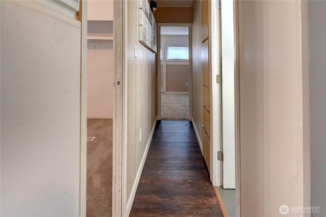 hallway featuring dark colored carpet and baseboards