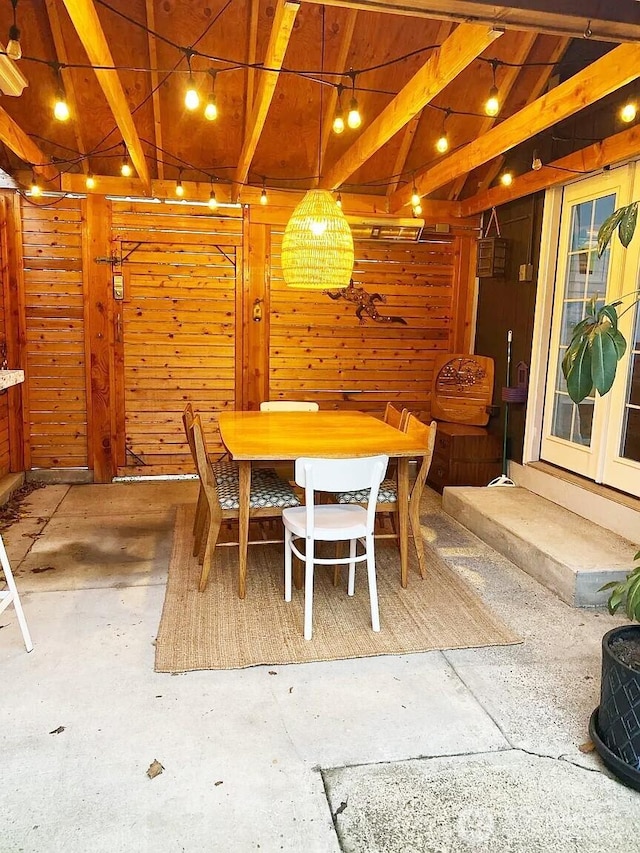 dining space with lofted ceiling with beams and wooden walls