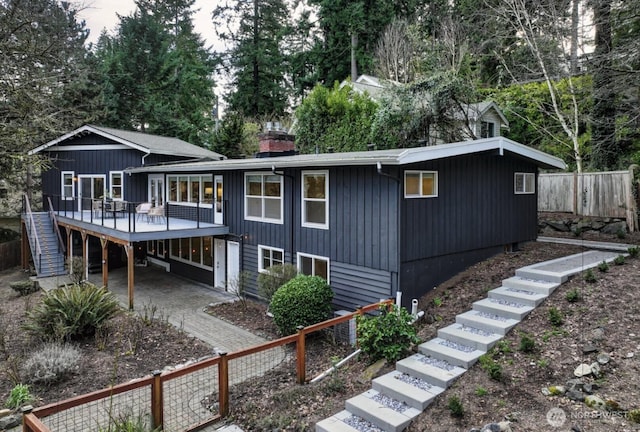 view of front of property featuring a patio, stairway, fence, a deck, and a carport