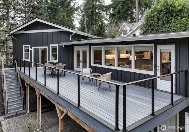 rear view of house with a deck, board and batten siding, and french doors