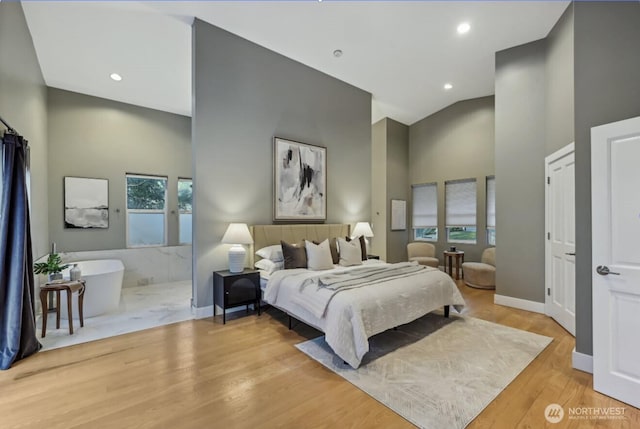 bedroom featuring baseboards, a high ceiling, wood finished floors, and recessed lighting