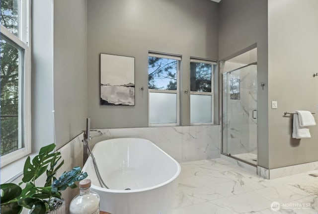 full bathroom featuring marble finish floor, plenty of natural light, a marble finish shower, and a soaking tub