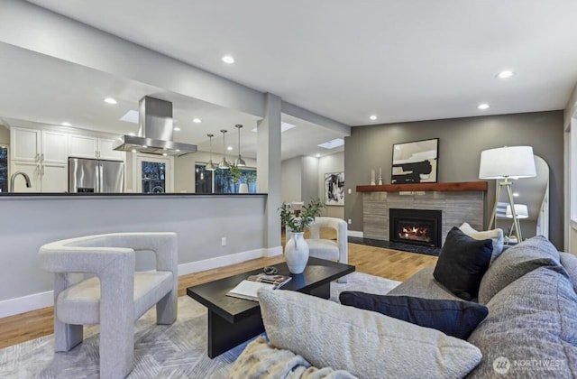 living room with recessed lighting, baseboards, a tiled fireplace, and wood finished floors