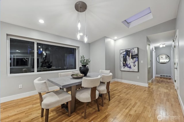 dining space with light wood finished floors, a skylight, baseboards, visible vents, and recessed lighting