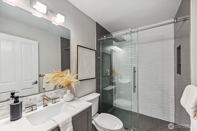 bathroom with a stall shower, vanity, and toilet