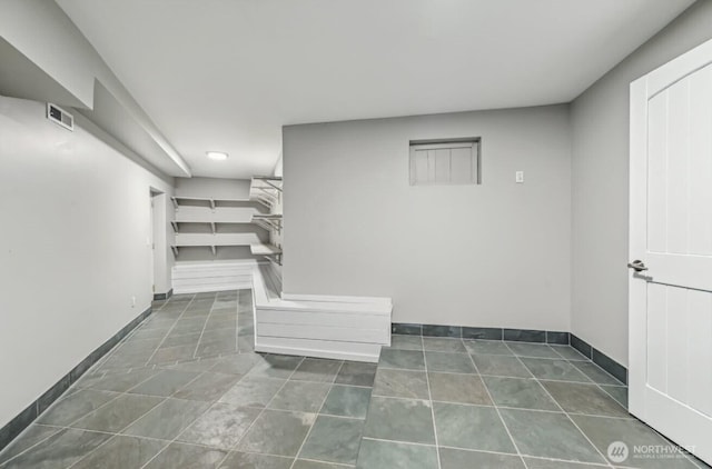 interior space with visible vents, dark tile patterned floors, and baseboards