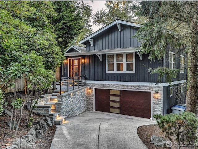 chalet / cabin with a garage, stone siding, board and batten siding, and concrete driveway