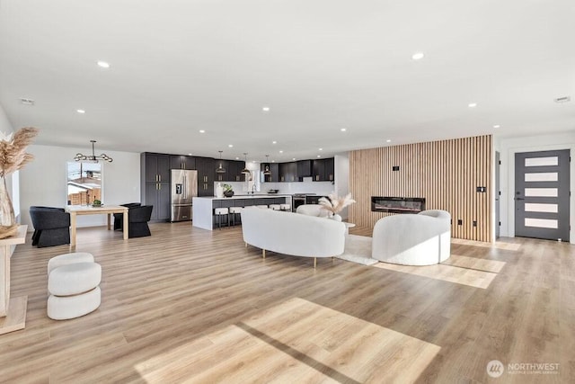 living area with a chandelier, light wood-type flooring, and recessed lighting