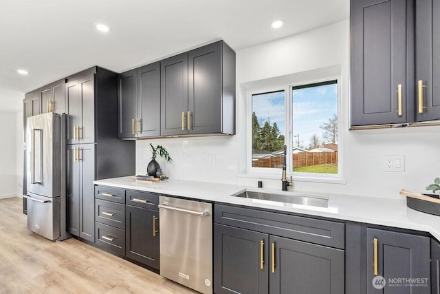 kitchen with light wood-style flooring, stainless steel appliances, a sink, and light countertops