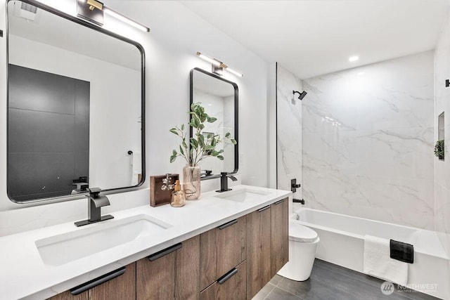 full bathroom featuring washtub / shower combination, double vanity, a sink, and toilet