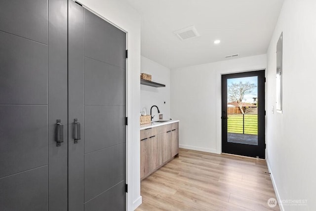 interior space with light wood-style flooring, baseboards, a sink, and recessed lighting