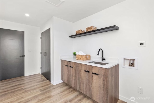 bar with baseboards, visible vents, a sink, and light wood finished floors