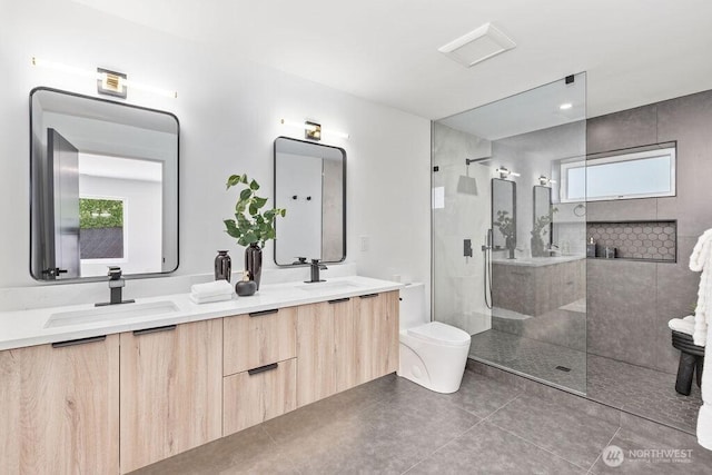 bathroom with toilet, double vanity, a walk in shower, and a sink