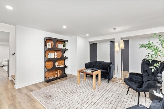 living area featuring recessed lighting, baseboards, light wood finished floors, and stairs