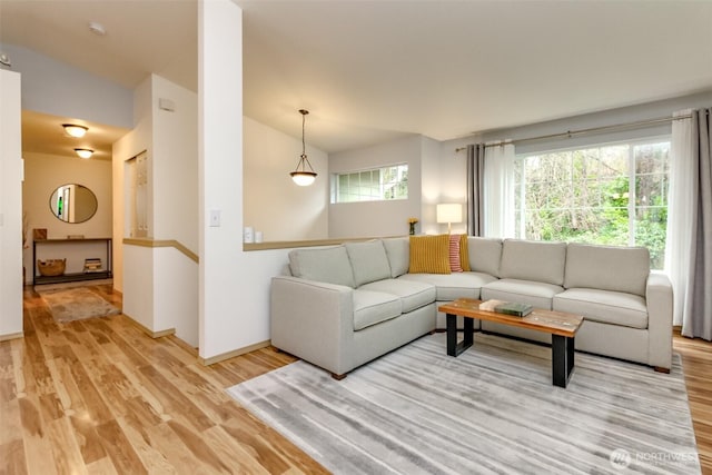 living room with lofted ceiling, baseboards, and light wood finished floors