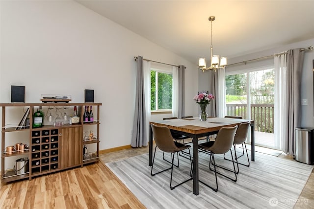 dining area with lofted ceiling, a notable chandelier, baseboards, and wood finished floors