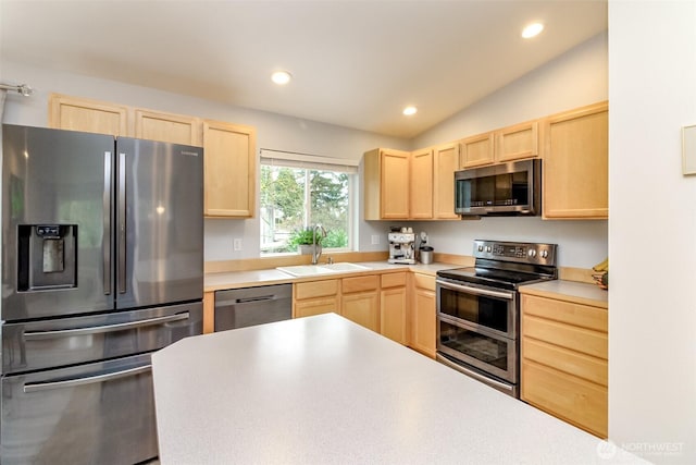 kitchen featuring lofted ceiling, light brown cabinets, stainless steel appliances, a sink, and light countertops