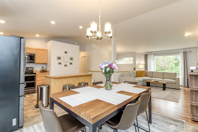 dining space featuring an inviting chandelier, light wood-style flooring, vaulted ceiling, and recessed lighting