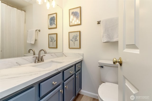 bathroom with toilet, baseboards, wood finished floors, and vanity