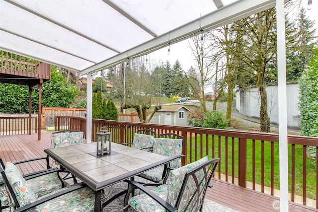 wooden terrace with fence, an outdoor structure, a lawn, and outdoor dining space