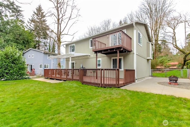 rear view of property featuring a deck, a yard, an outdoor fire pit, and fence