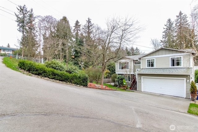 view of front of house with a shingled roof, concrete driveway, an attached garage, board and batten siding, and stairs