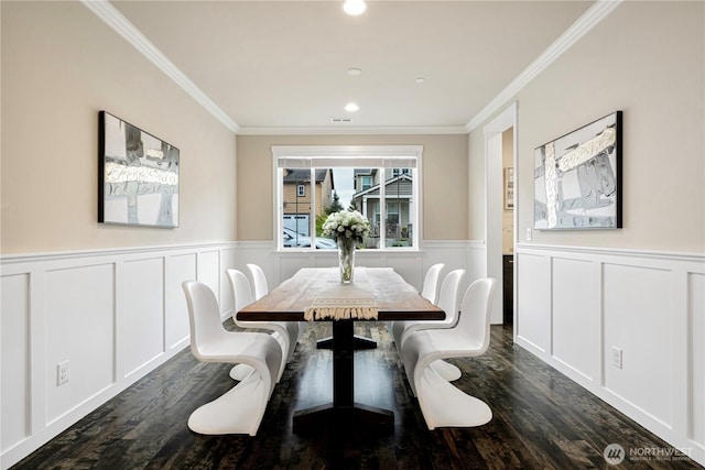 dining area featuring a wainscoted wall, ornamental molding, and dark wood-style flooring