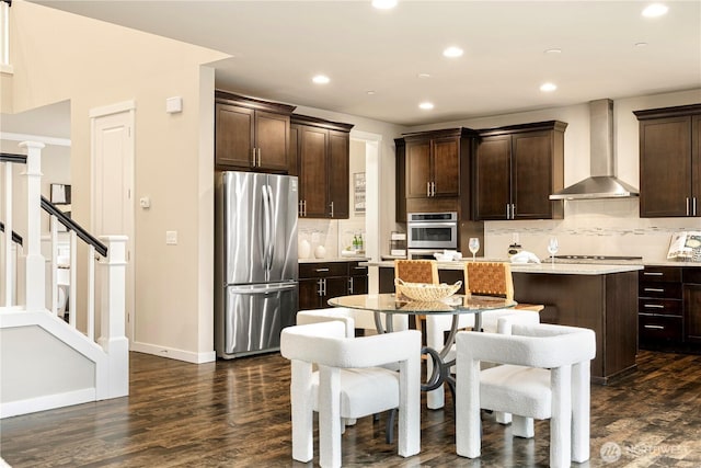 kitchen featuring stainless steel appliances, dark brown cabinets, wall chimney exhaust hood, and a kitchen island