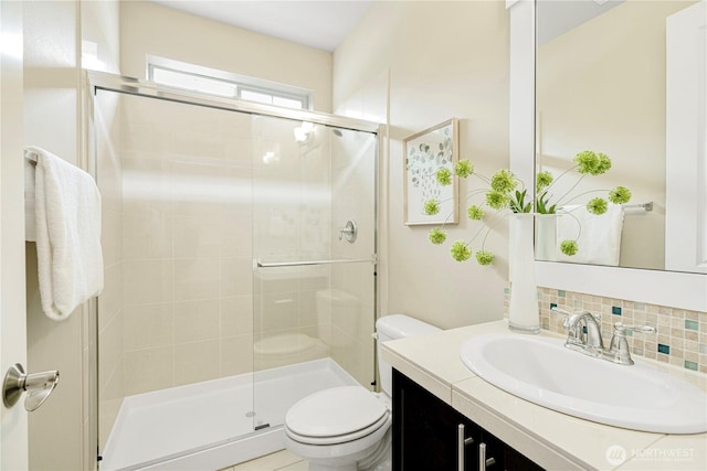 full bathroom featuring toilet, a stall shower, decorative backsplash, and vanity