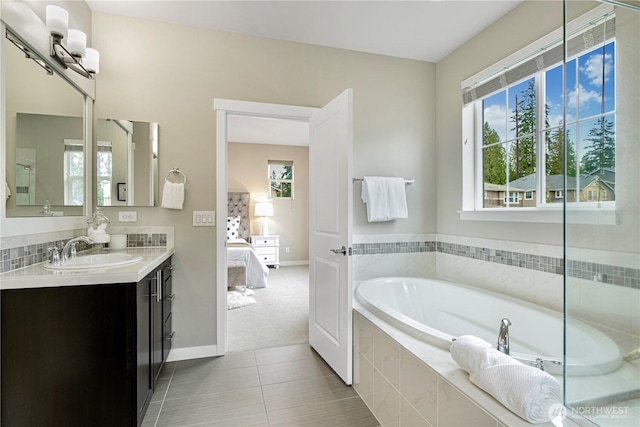 ensuite bathroom featuring a garden tub, vanity, ensuite bath, tile patterned flooring, and baseboards