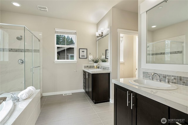 bathroom featuring a stall shower, visible vents, a garden tub, and a sink