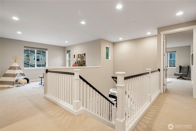 hallway with carpet floors, recessed lighting, baseboards, and an upstairs landing