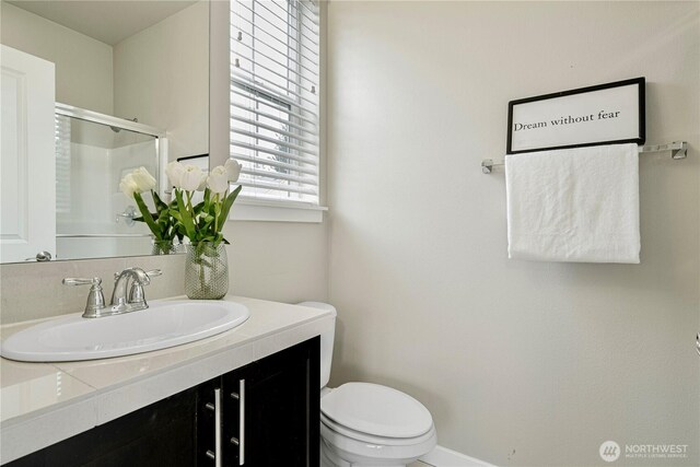 full bath featuring toilet, a stall shower, and vanity