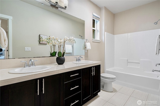 bathroom with toilet, double vanity, a sink, and shower / bathtub combination