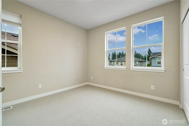 carpeted empty room featuring visible vents and baseboards