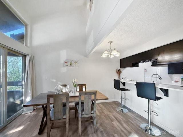 dining area with a notable chandelier, a textured ceiling, baseboards, and wood finished floors