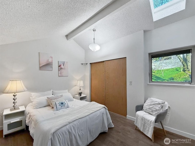 bedroom with a textured ceiling, vaulted ceiling with skylight, a closet, and wood finished floors