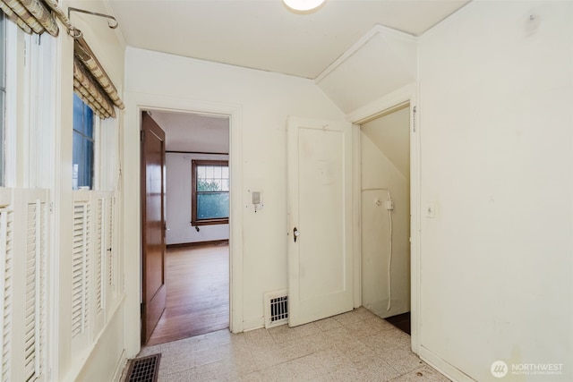 corridor featuring light floors, baseboards, and visible vents