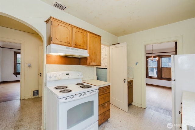 kitchen featuring under cabinet range hood, white appliances, visible vents, light countertops, and light floors