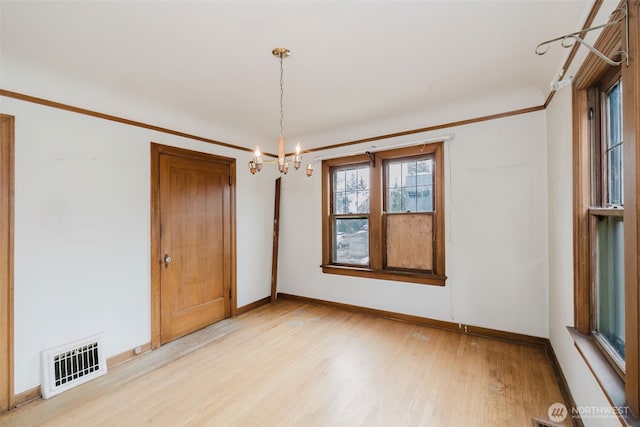 unfurnished room featuring visible vents, light wood-style floors, ornamental molding, a chandelier, and baseboards