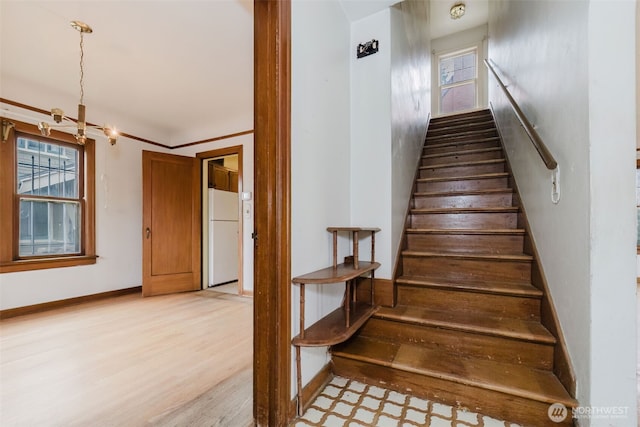 staircase featuring a notable chandelier, baseboards, and wood finished floors