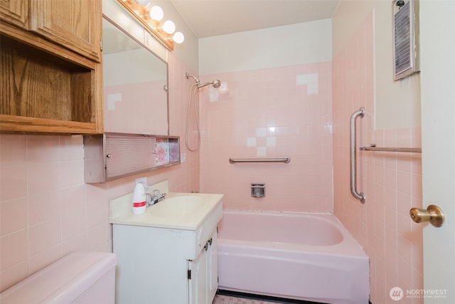 bathroom with vanity, tile walls, toilet, and bathing tub / shower combination