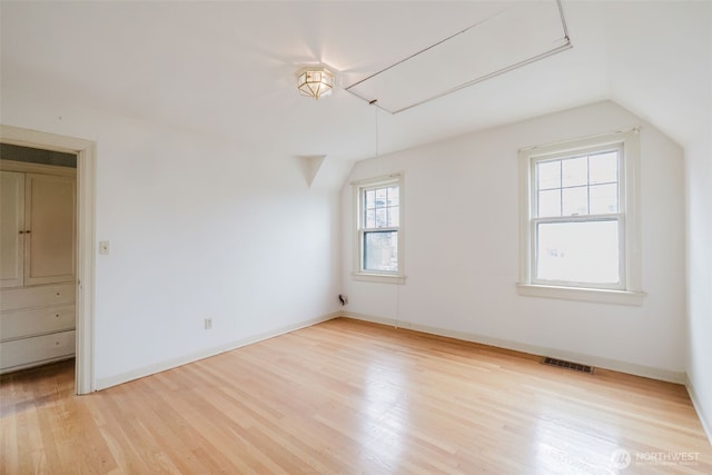 bonus room featuring lofted ceiling, wood finished floors, visible vents, baseboards, and attic access