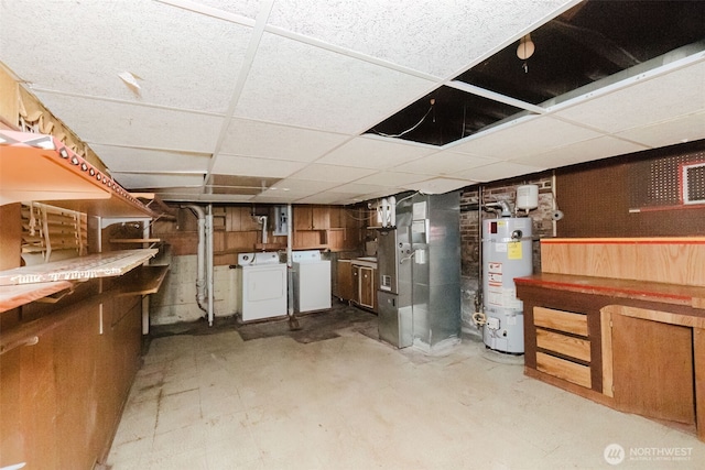 unfinished basement with water heater, a drop ceiling, and washer and dryer