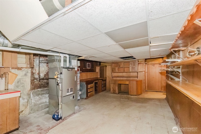 finished basement featuring a drop ceiling and heating unit