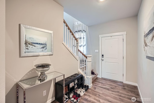 foyer entrance with wood finished floors, baseboards, and stairs