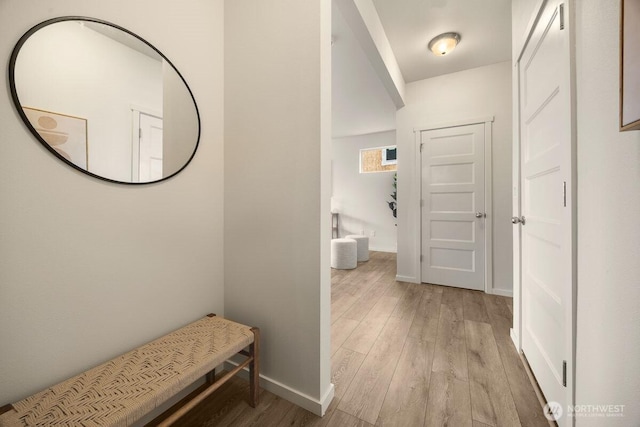 corridor with baseboards and light wood-style floors