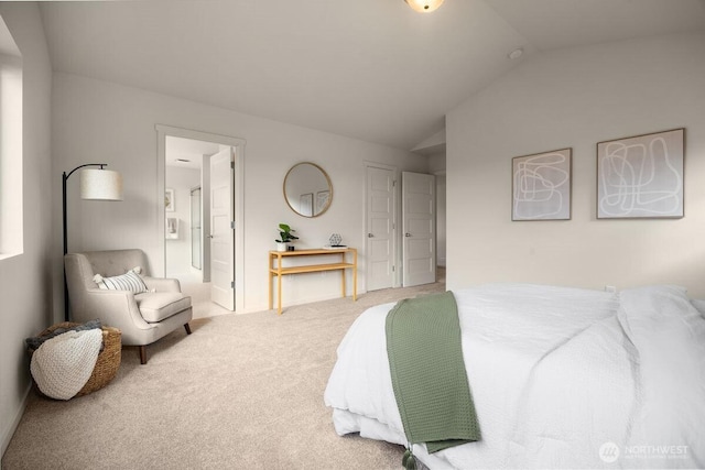 carpeted bedroom with ensuite bath and lofted ceiling